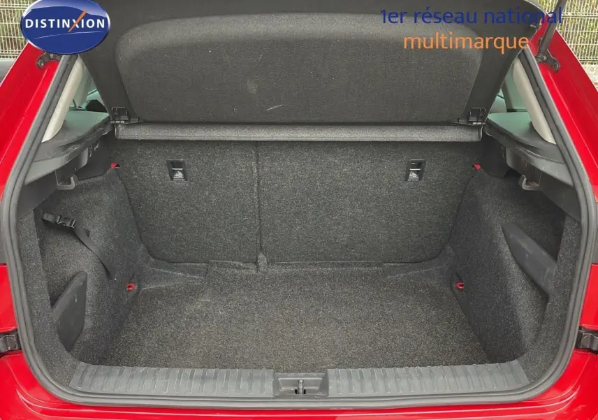 Coffre ouvert d’un Skoda Kamiq rouge Velvet Metal, montrant un espace de chargement propre et bien agencé.