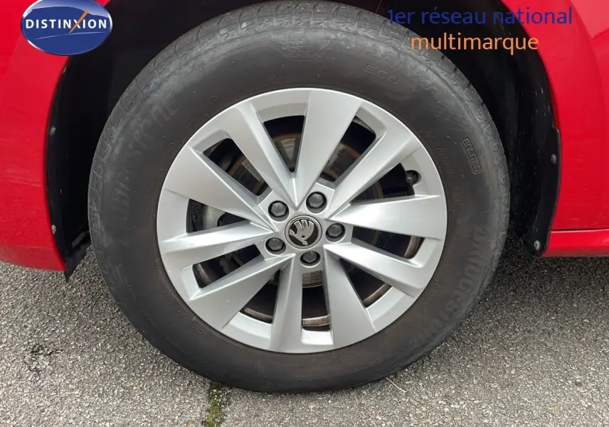 Gros plan sur la roue avant gauche d'une Skoda Kamiq rouge Velvet Metal avec jante alliage argentée.