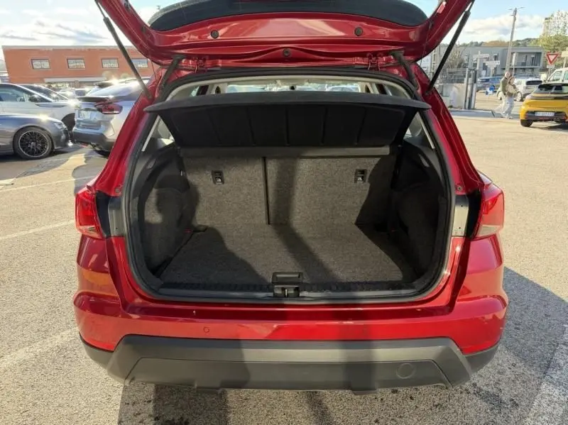 Vue arrière du coffre ouvert d'un SEAT Arona rouge métal 2019, mettant en valeur l'espace de chargement vide.