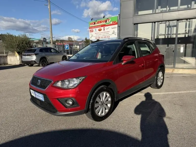 SEAT Arona rouge métal vue 3/4 avant droit, SUV compact avec toit noir et jantes alliage, stationné en extérieur.
