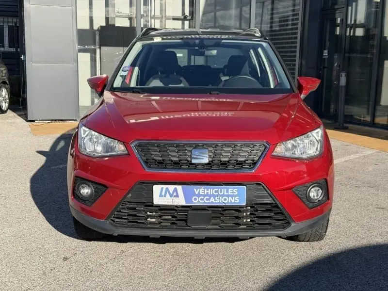 Vue de face d'un SEAT Arona rouge métal 2019 avec calandre noire et plaque "Véhicules Occasions" visible.