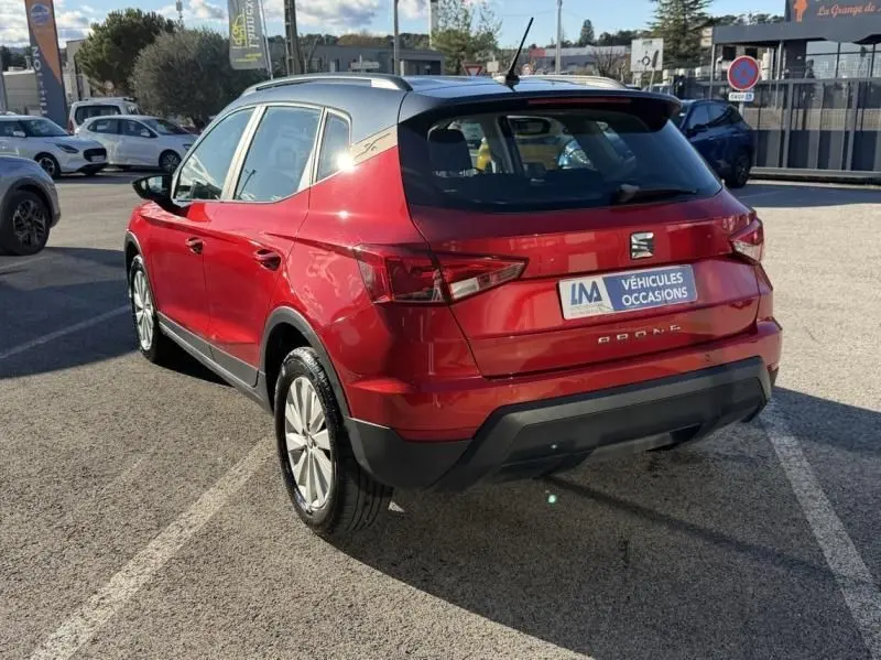 Vue 3/4 arrière droite d'un SEAT Arona rouge métal 2019 avec toit argenté et badge Style visible sur le montant arrière.