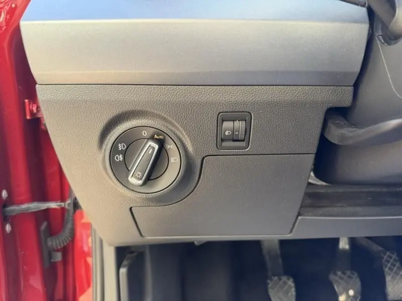 Détail du tableau de bord côté gauche du SEAT Arona rouge métal 2019, avec commande des phares et réglage de hauteur.