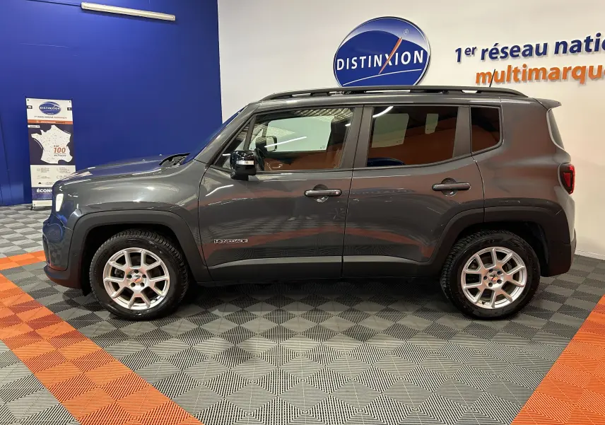 Vue de profil côté gauche d'un Jeep Renegade gris graphite 2023 avec toit ouvrant et jantes argentées en showroom.