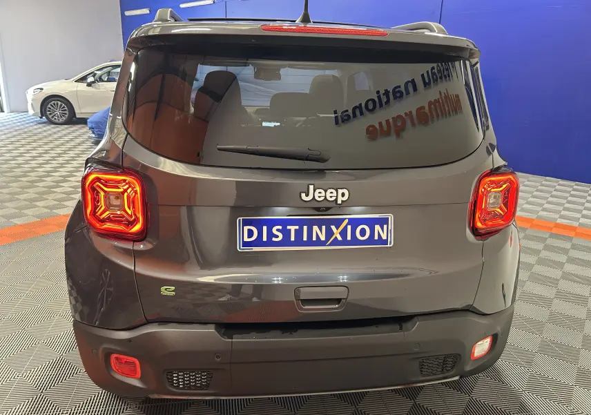 Vue arrière d'une Jeep Renegade gris graphite avec feux allumés dans un showroom.