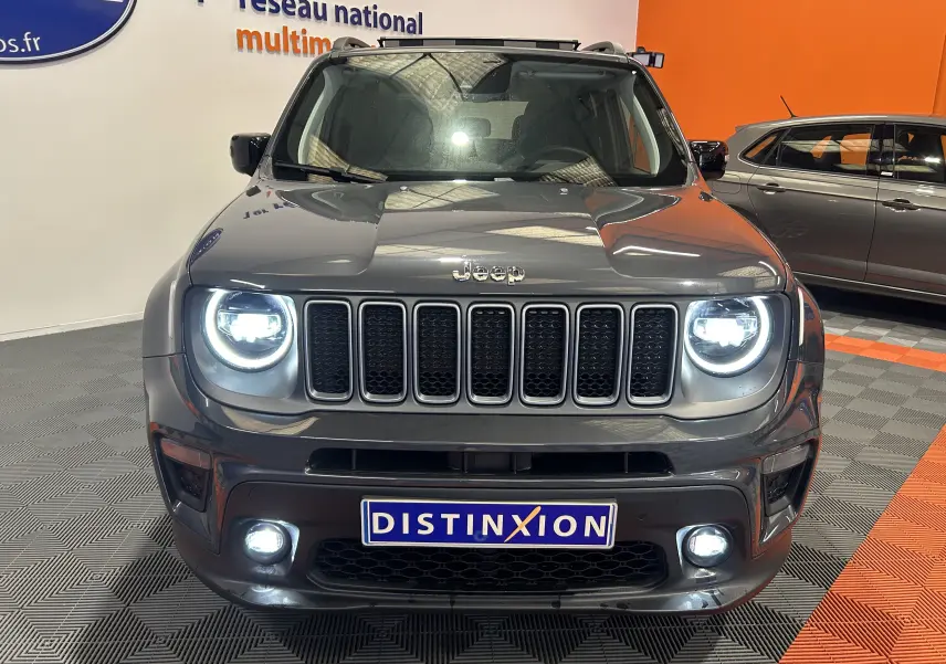 Vue de face d'un Jeep Renegade gris graphite 2023 avec phares LED allumés dans un showroom.