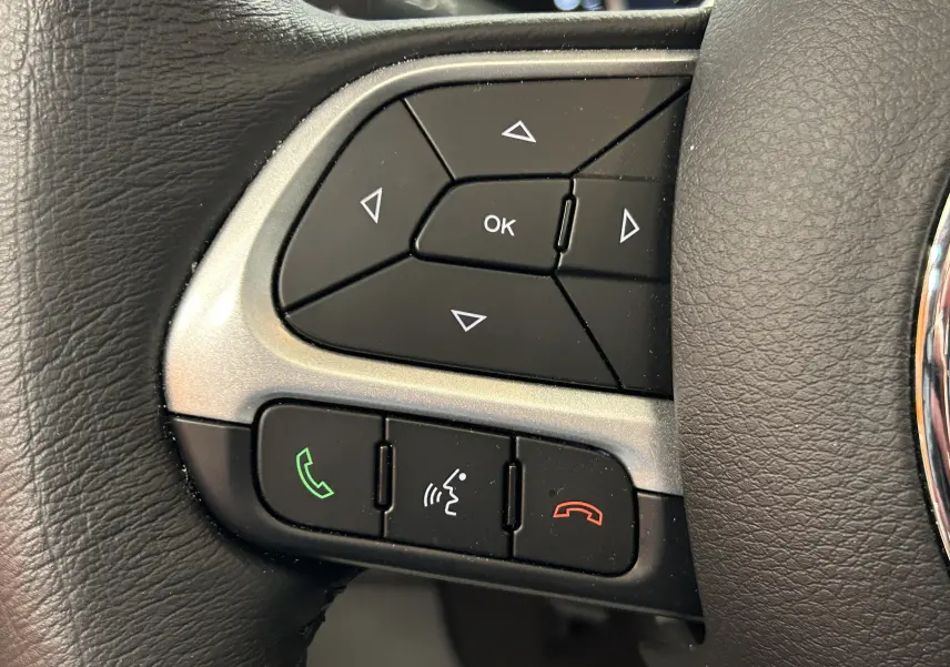 Gros plan sur les commandes multifonctions noires du volant en cuir du Jeep Renegade 2023, avec boutons appel et navigation.