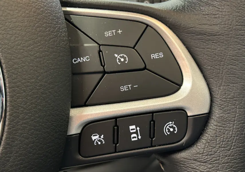 Gros plan sur les boutons de régulateur de vitesse au volant cuir noir du Jeep Renegade Turbo T4 MHEV 130 Limited 2023.