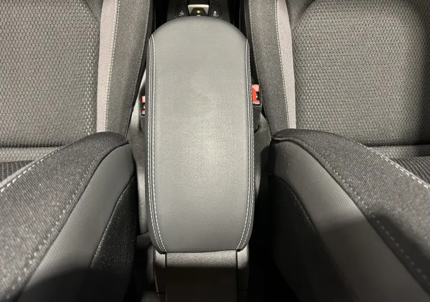 Vue plongeante sur l'accoudoir central en cuir noir avec surpiqûres blanches entre les sièges tissu gris du Jeep Renegade 2023.