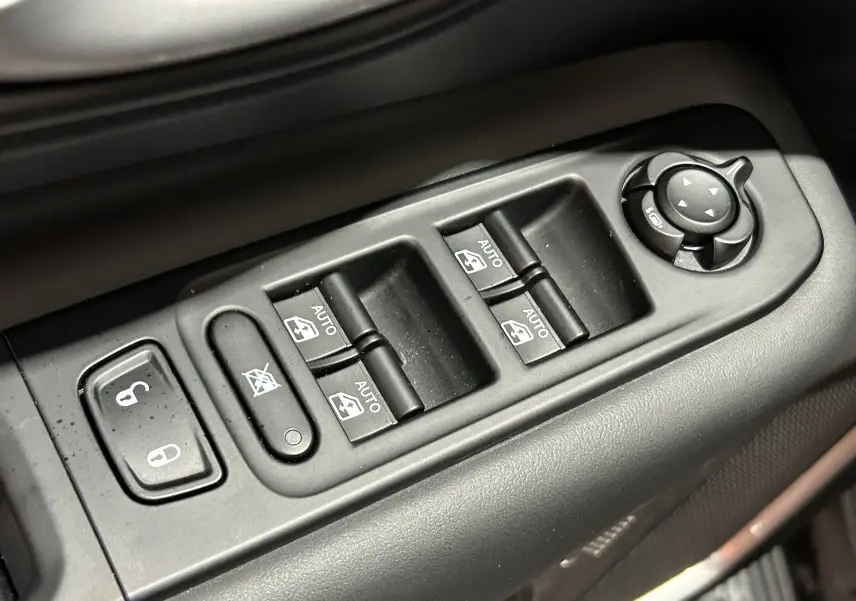 Gros plan sur les commandes de lève-vitres et rétroviseurs côté conducteur du Jeep Renegade 2023 gris graphite.