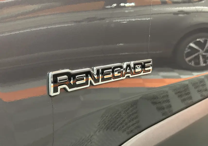 Gros plan sur l’inscription Renegade sur la porte côté gauche d’un Jeep Renegade gris graphite.