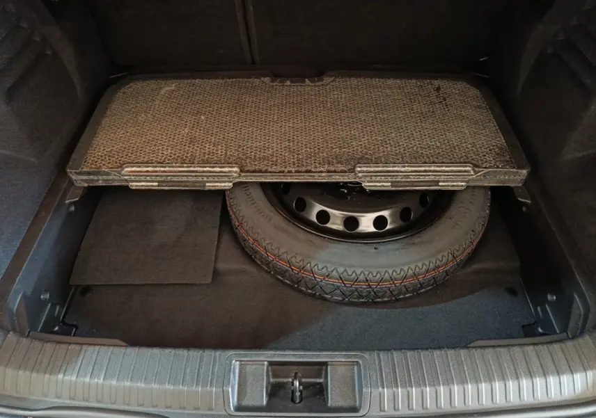 Vue plongeante sur le coffre ouvert du Renault Symbioz 2025, montrant la roue de secours sous le plancher noir.