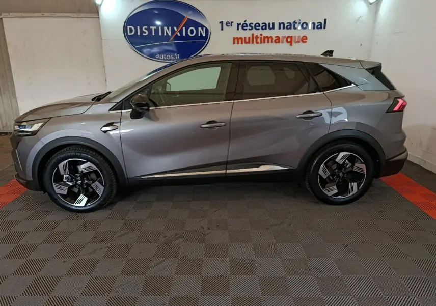 Profil droit du Renault SYMBIOZ 2025 gris métallisé avec jantes noires et détails modernes en intérieur showroom.