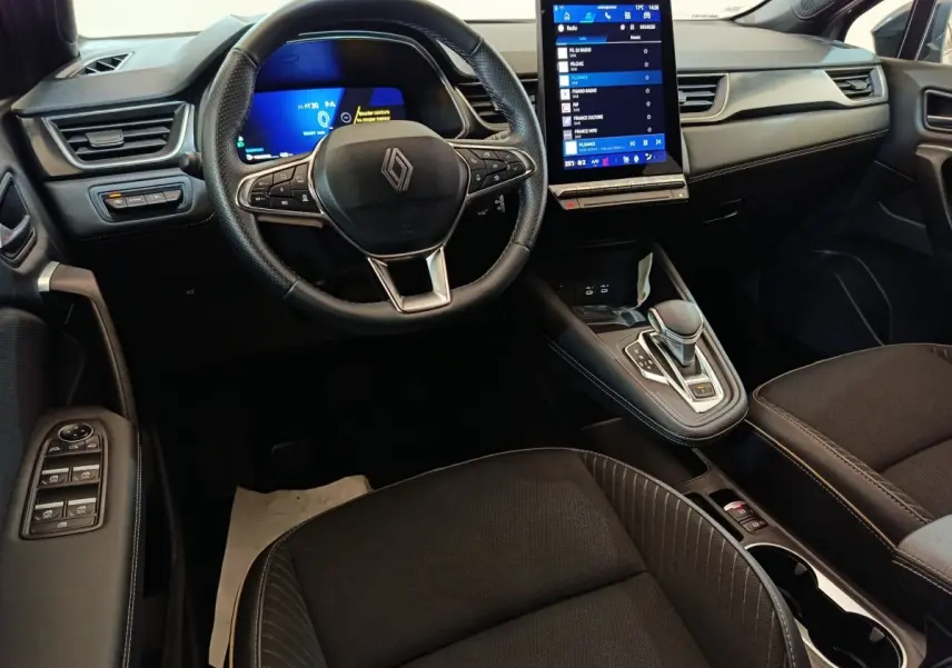 Vue intérieure avant du Renault SYMBIOZ 2025, tableau de bord noir avec écran tactile vertical et volant multifonctions.