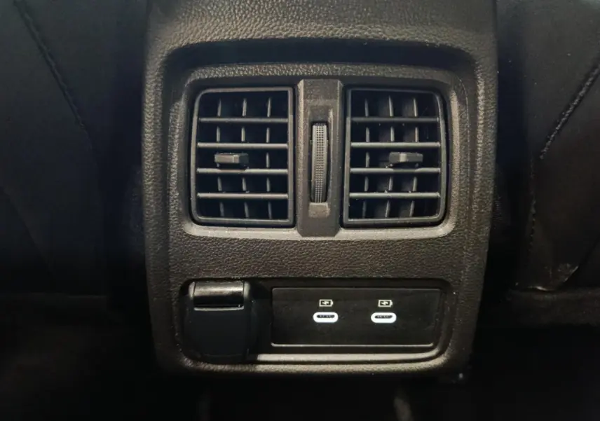 Gros plan sur la console arrière noire du Renault Symbioz avec bouches d’aération et ports USB-C éclairés.