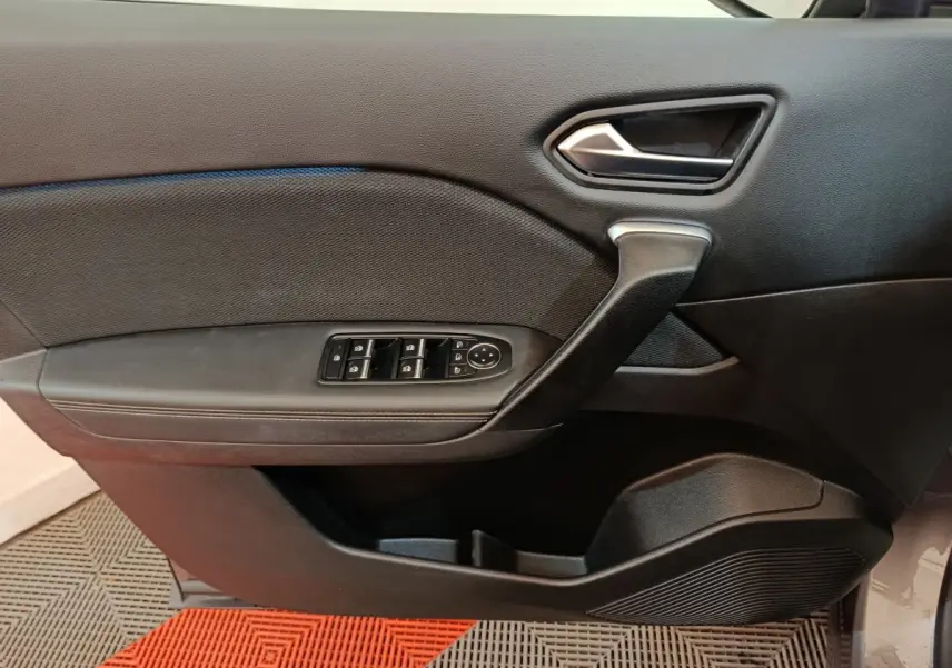 Vue intérieure du panneau de porte avant gauche de la Renault Symbioz 2025, avec commandes de vitres et poignée noire.