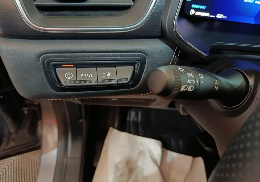 Gros plan sur les commandes noires du tableau de bord côté gauche du Renault Symbioz 2025 avec éclairage bleu à l'écran.