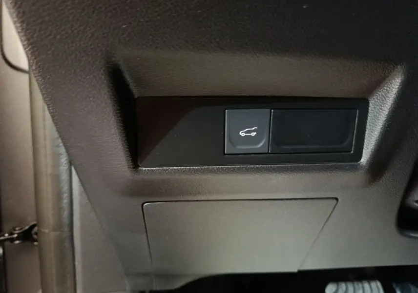 Bouton d'ouverture du coffre noir sur tableau de bord intérieur côté conducteur d'une Renault Symbioz hybride 2025.