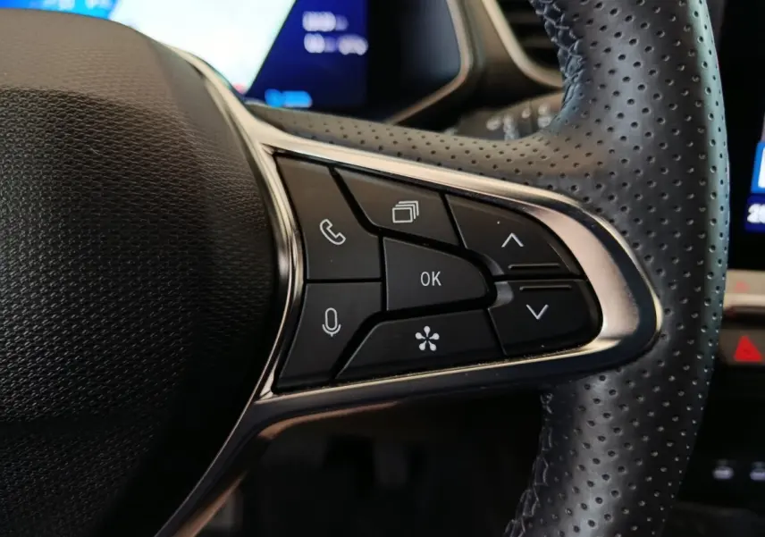 Gros plan sur les commandes multifonctions à droite du volant perforé noir du Renault Symbioz 2025 hybride.