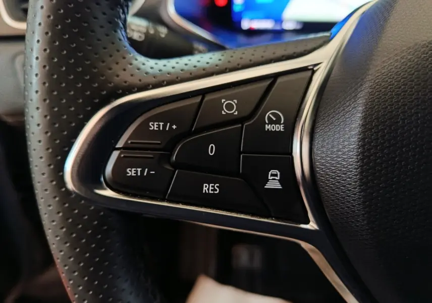 Gros plan sur les commandes noires du volant perforé côté gauche du Renault Symbioz hybride 2025, avec chrome brillant.