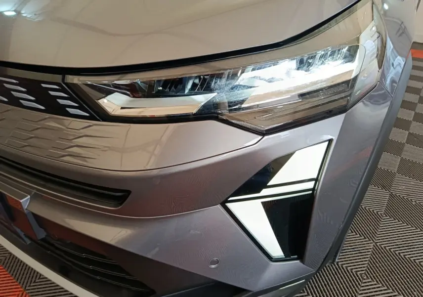 Gros plan sur l'avant droit gris métallisé du Renault Symbioz 2025, mettant en valeur ses phares LED et feux de jour distinctifs.
