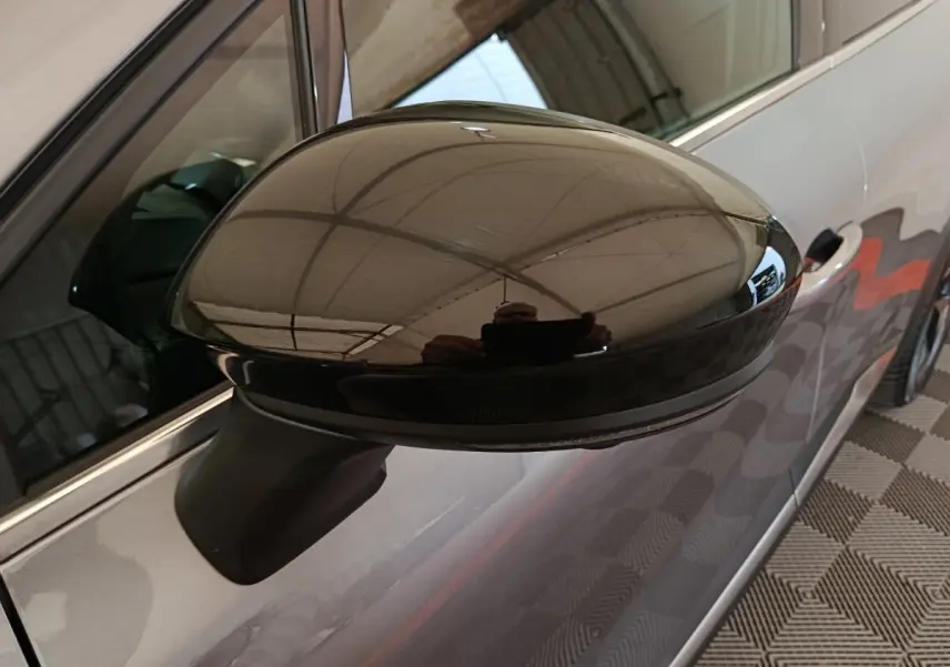 Gros plan sur le rétroviseur droit noir brillant du Renault Symbioz 2025, avec carrosserie gris clair visible en arrière-plan.