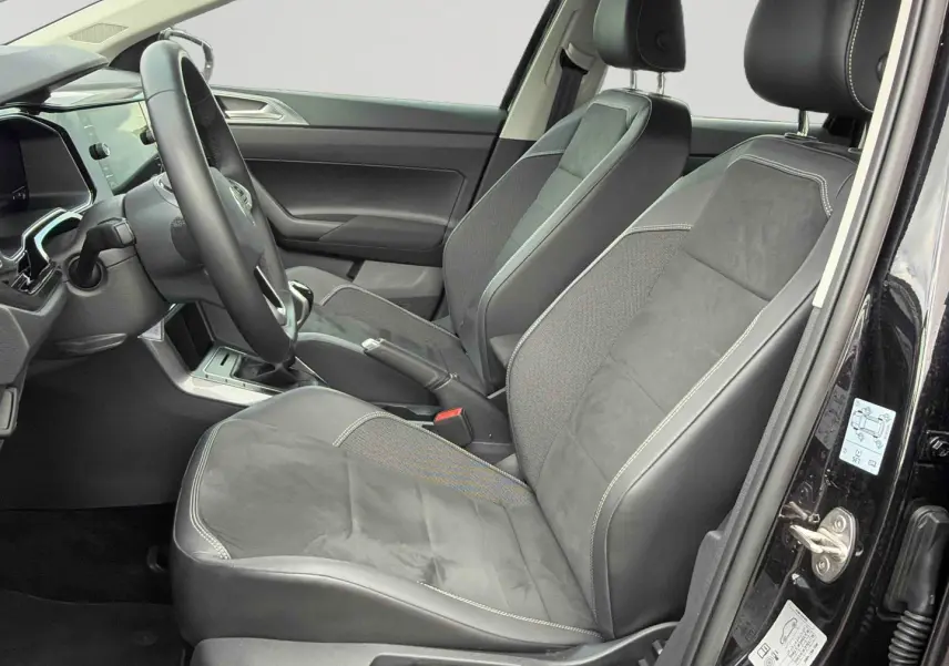 Vue intérieure côté conducteur de la Volkswagen Polo noire 2025, sièges en cuir et alcantara avec coutures contrastées.