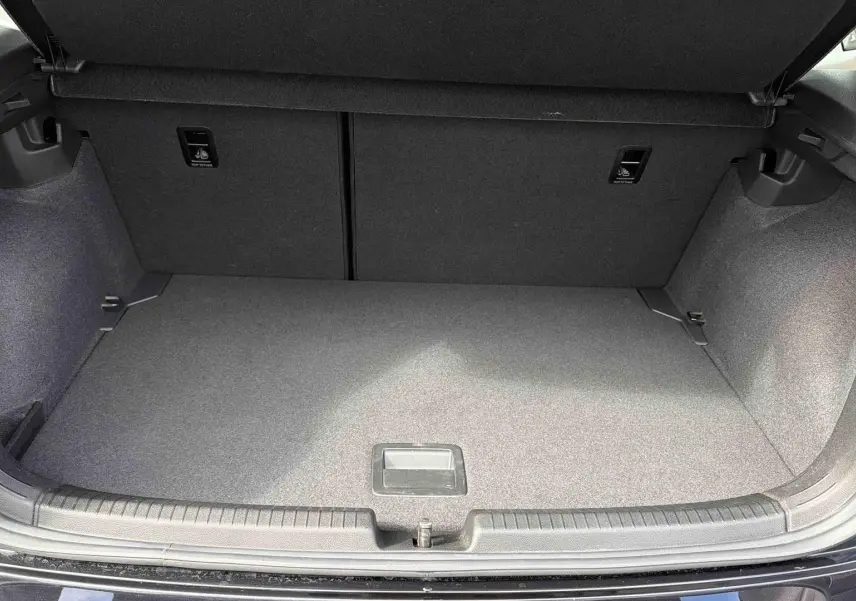 Coffre ouvert vu de l'arrière d'une Volkswagen Polo noire, montrant un espace de chargement propre et vide.