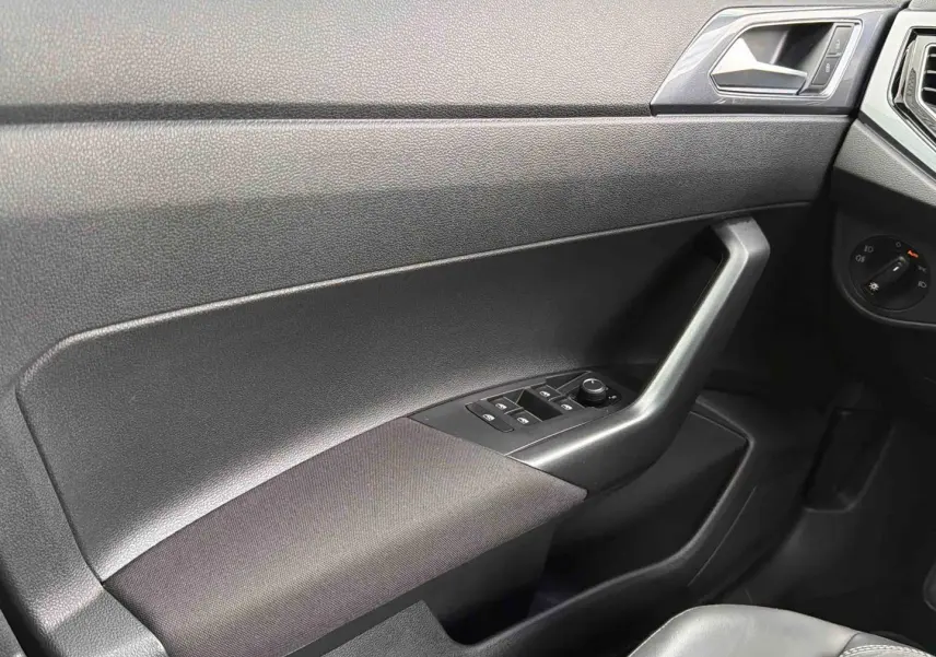 Vue intérieure côté conducteur de la porte noire de la Volkswagen Polo 2025 avec commandes des vitres et rétroviseurs.
