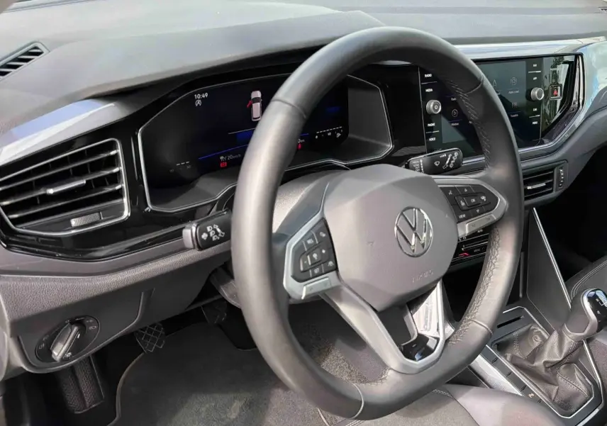 Vue intérieure rapprochée du volant cuir multifonctions et du tableau de bord digital de la Volkswagen Polo noire 2025.