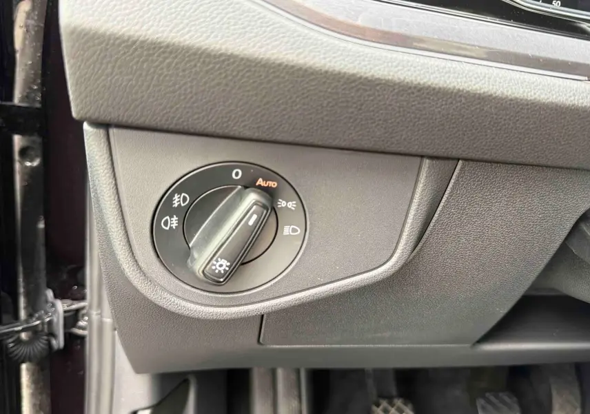 Gros plan sur le bouton de commande des phares à gauche du tableau de bord d'une Volkswagen Polo noire 2025.