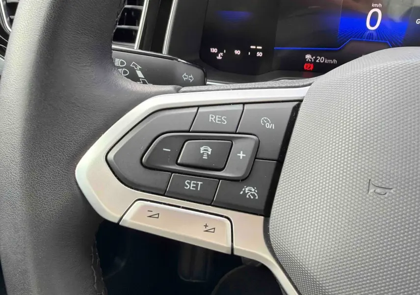 Gros plan sur le volant cuir gris de la Volkswagen Polo 2025, avec commandes du régulateur adaptatif et tableau de bord digital.