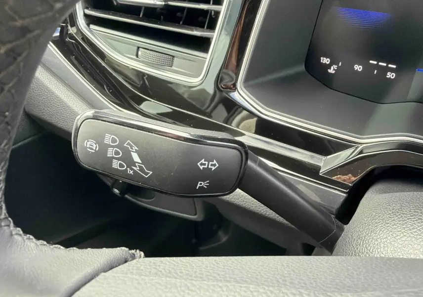 Gros plan sur le commodo de clignotants noir à gauche du volant dans l’habitacle d’une Volkswagen Polo noire.
