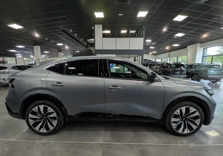 Vue latérale droite d’un Renault Rafale gris Schiste Satin en showroom, soulignant ses jantes bicolores et lignes fluides.