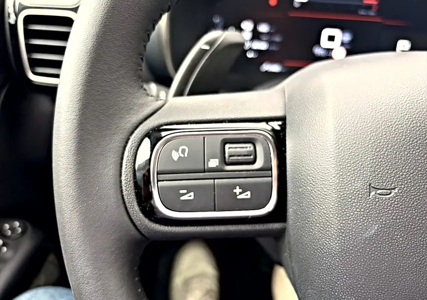 Gros plan sur les commandes gauche du volant cuir noir du Citroën C5 Aircross 2025, avec touches multifonctions.