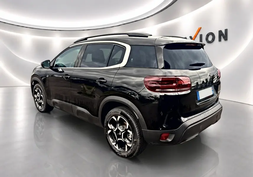 Citroën C5 Aircross noir vue 3/4 arrière droit, avec barres de toit et jantes alu distinctives.