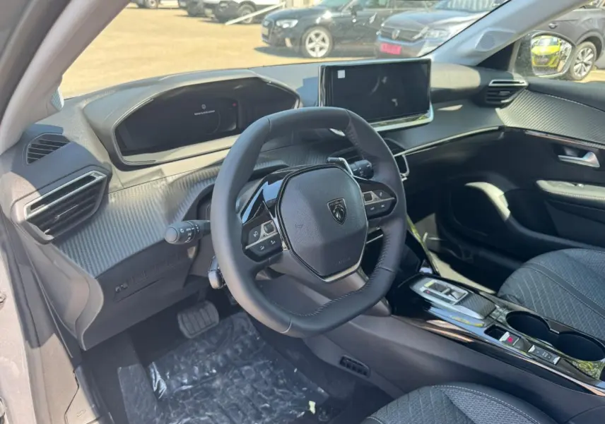 Vue intérieure côté conducteur du Peugeot 208 Hybrid 110 gris, avec volant compact et écran tactile central.