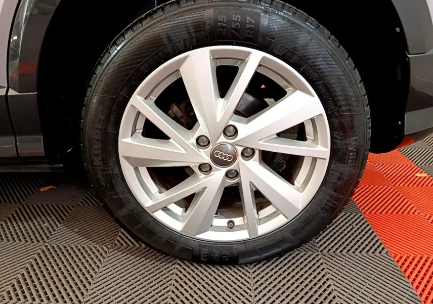 Gros plan sur la roue avant droite d’un Audi Q2 gris clair, mettant en valeur la jante alliage à 5 doubles branches.