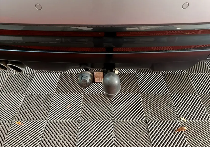 Gros plan sur l'attelage de remorque à l'arrière d'un Audi Q2 gris clair, avec double sortie d'échappement visible.
