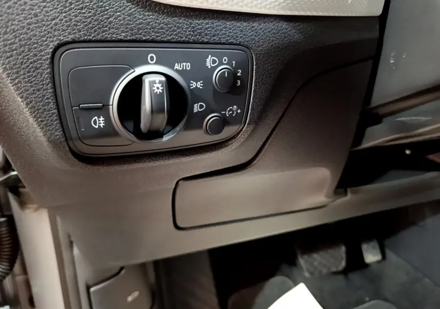 Gros plan sur le panneau de commande des phares à gauche du volant dans l'Audi Q2 35 TDI 150 Design gris clair de 2020.