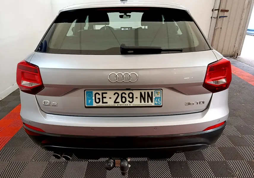 Vue arrière d'un Audi Q2 gris clair 35 TDI 150 Design avec double sortie d'échappement et attelage de remorque.