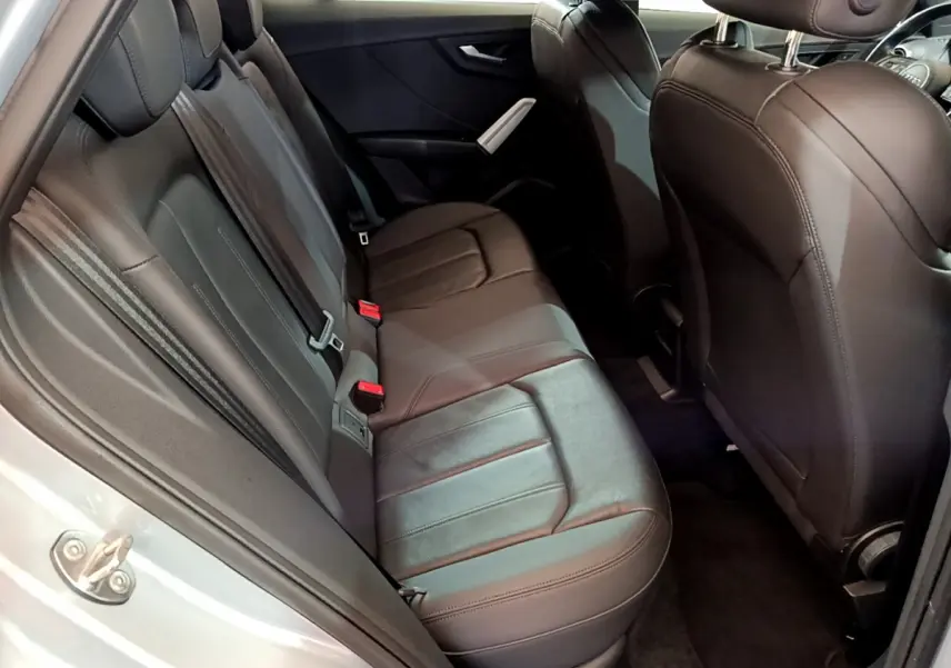 Vue côté gauche sur l’intérieur arrière de l’Audi Q2 35 TDI 150 Design 2020 avec sièges en cuir noir et portière grise ouverte.