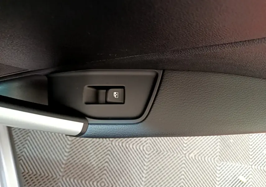 Gros plan sur le bouton de commande de la vitre électrique côté conducteur de l’Audi Q2 gris clair 2020.