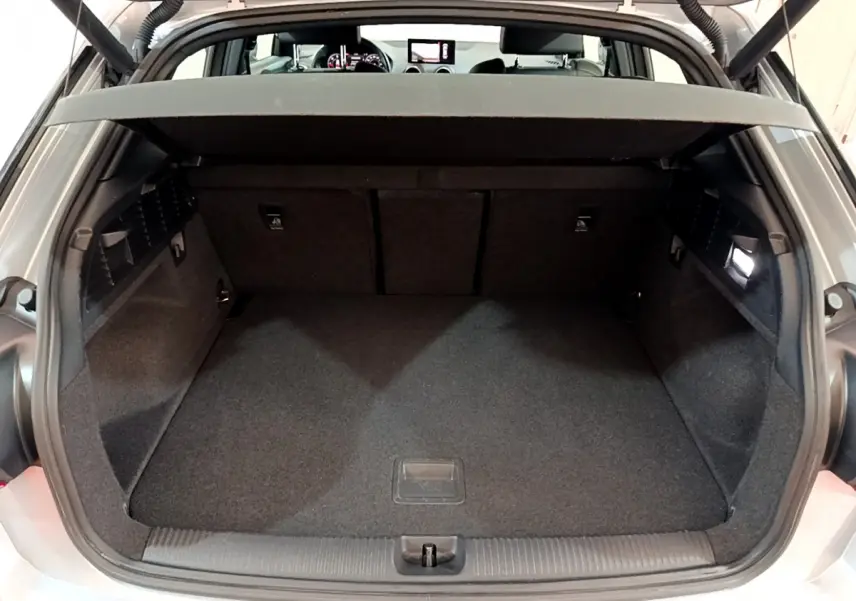 Coffre ouvert d’un Audi Q2 gris clair, vue arrière montrant l’espace de chargement et la tablette de séparation.