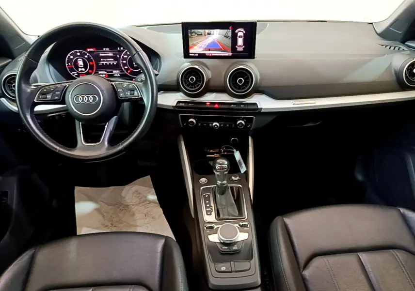 Vue intérieure de l'Audi Q2 35 TDI 150 Design 2020, tableau de bord noir avec écran central et volant cuir multifonctions.