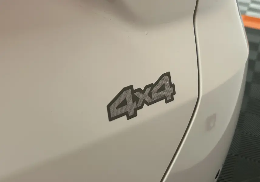 Gros plan sur l’inscription 4x4 en relief sur la carrosserie blanche arrière droite du Dacia Duster 2024.