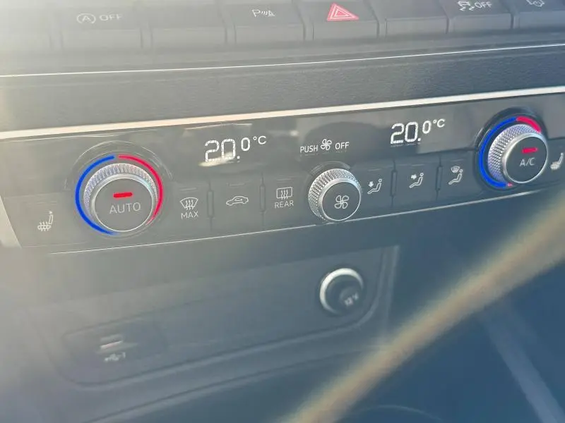 Gros plan sur la console centrale de la climatisation automatique de l'Audi Q2 blanche, affichant 20°C des deux côtés.