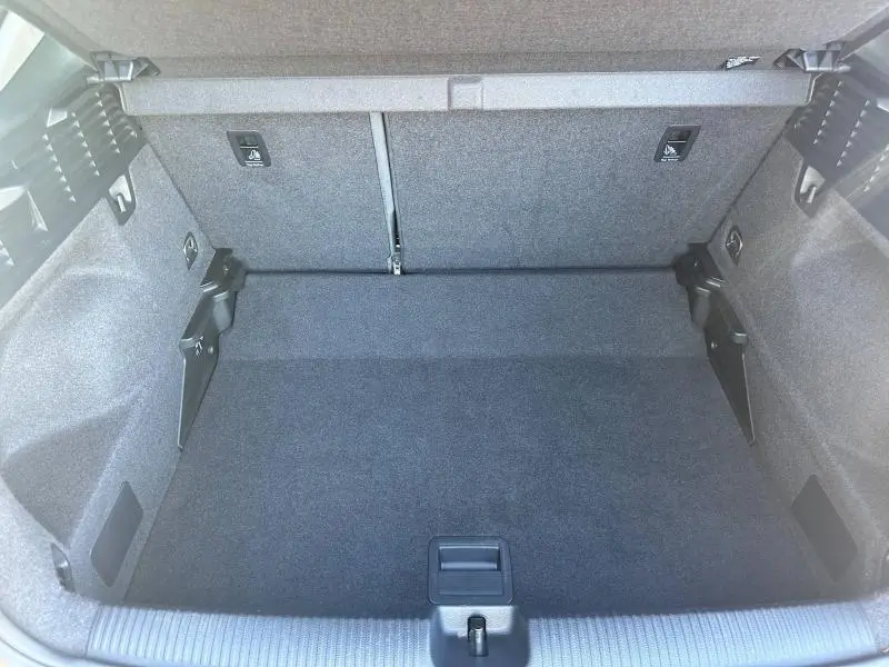 Coffre spacieux et propre de l'Audi Q2 blanc, vue intérieure arrière avec banquette rabattable et finitions en tissu gris.