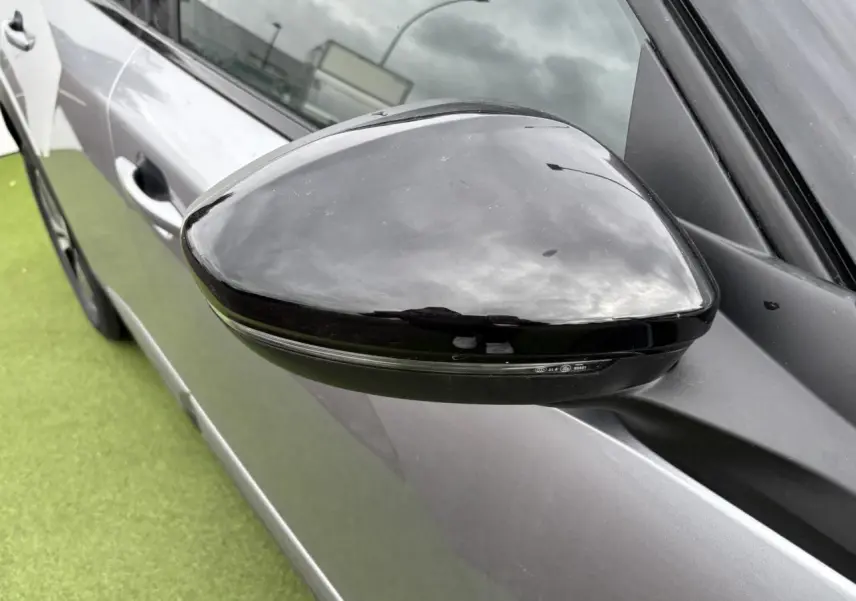 Rétroviseur noir brillant côté gauche du Peugeot 2008 gris Artense avec toit noir, vue rapprochée en extérieur.