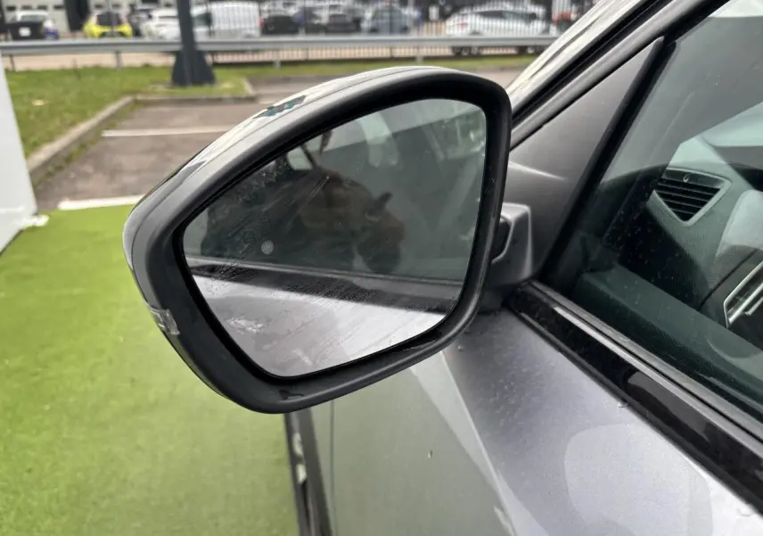 Rétroviseur extérieur côté gauche du Peugeot 2008 gris Artense avec toit noir, vue rapprochée sur la portière avant.